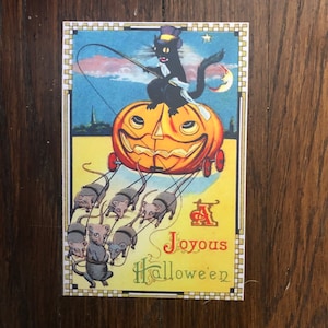 May include: Vintage Halloween postcard featuring a black cat in a top hat riding a jack-o'-lantern carriage pulled by six mice. The postcard has a yellow background with the words "Joyous Halloween".