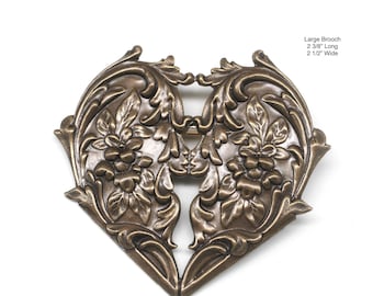 May include: A large, ornate, heart-shaped brooch made of bronze with a floral design. It measures 2 3/8" long and 2 1/2" wide.