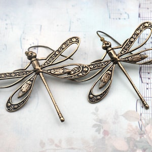 May include: A white ceramic mug with a black handle and the text "But First, Coffee" in a bold, black font. The mug is set against a blurred background, highlighting its clean design.