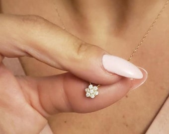 May include: A delicate gold chain necklace with a small flower pendant featuring clear sparkling stones.