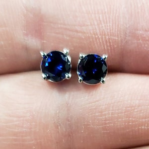 May include: A pair of silver stud earrings with dark blue round gemstones.