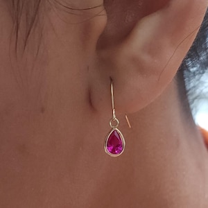 Puede incluir: Un par de pendientes de oro con una piedra preciosa rosa en forma de lágrima.