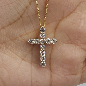 May include: A gold chain necklace with a diamond-encrusted cross pendant.