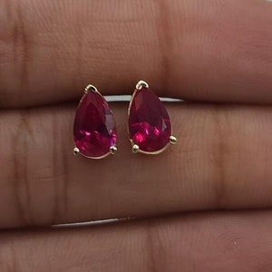 May include: A pair of gold teardrop earrings with red gemstone accents.