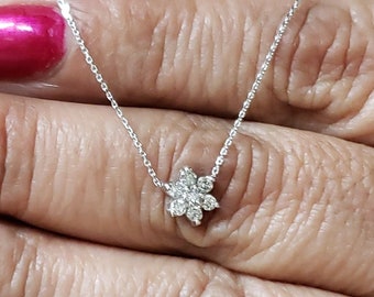 May include: A delicate silver chain necklace with a small flower-shaped pendant set with sparkling diamonds.
