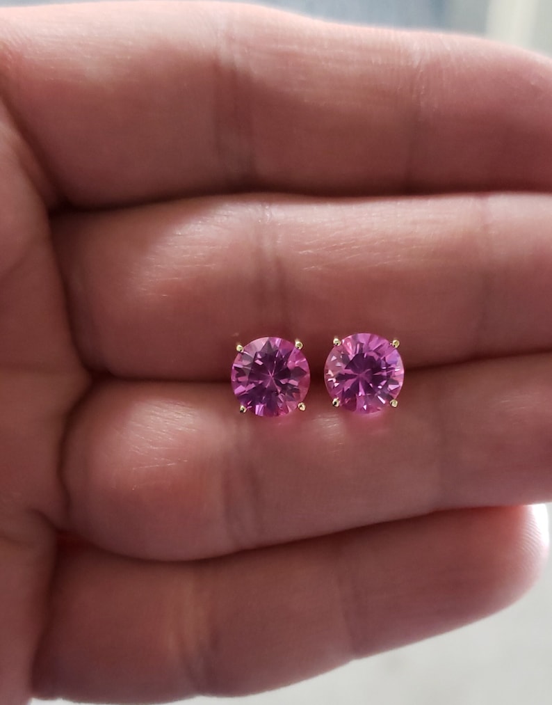 May include: A pair of gold stud earrings with pink round gemstones.