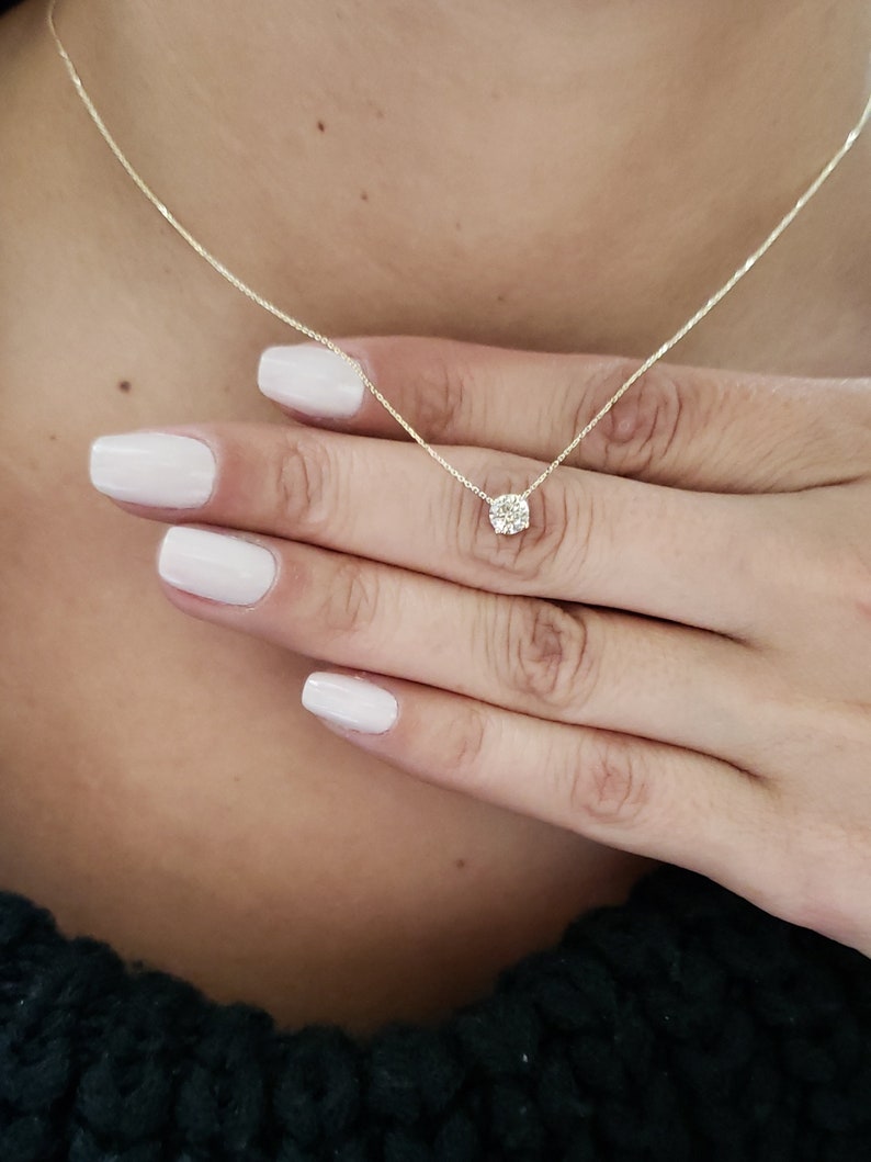 Puede incluir: Un delicado collar de cadena de oro con un peque&ntilde;o colgante redondo de diamante transparente.