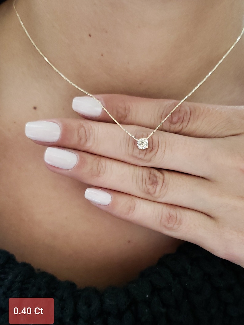 Puede incluir: Un delicado collar de cadena de oro con un peque&ntilde;o colgante redondo de diamante. El diamante est&aacute; engastado en un halo de diamantes m&aacute;s peque&ntilde;os. El collar es de 0,40 quilates.