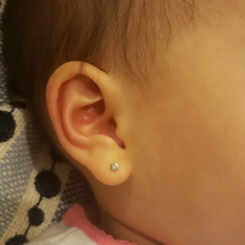 Puede incluir: Primer plano de la oreja de un beb&eacute; con un peque&ntilde;o pendiente de diamante.
