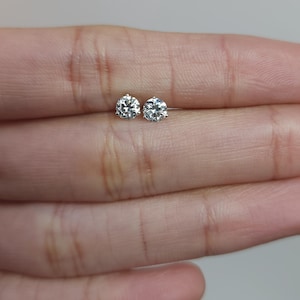 May include: A pair of small, round, clear diamond stud earrings.
