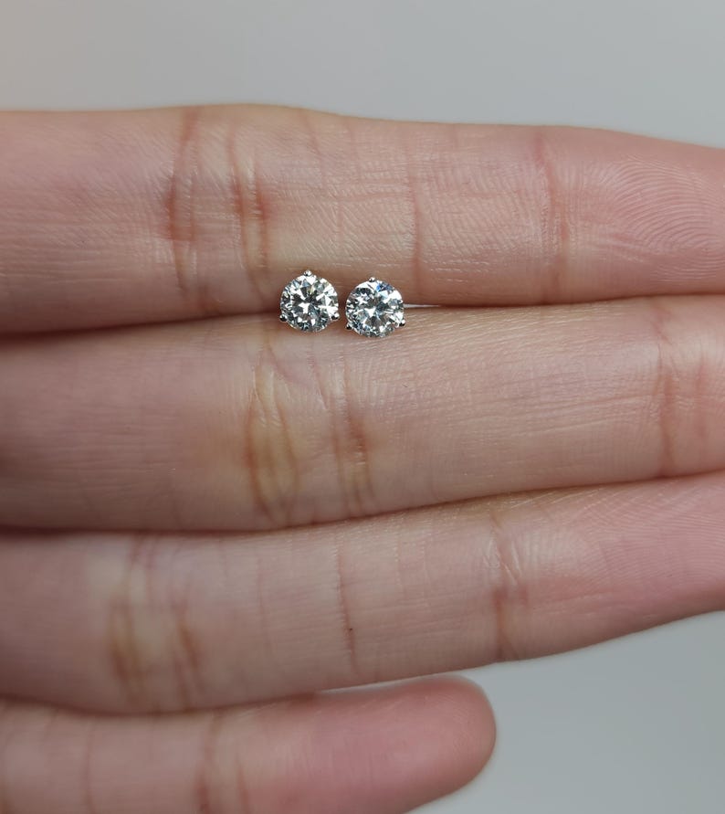 May include: A pair of small, round, clear diamond stud earrings.
