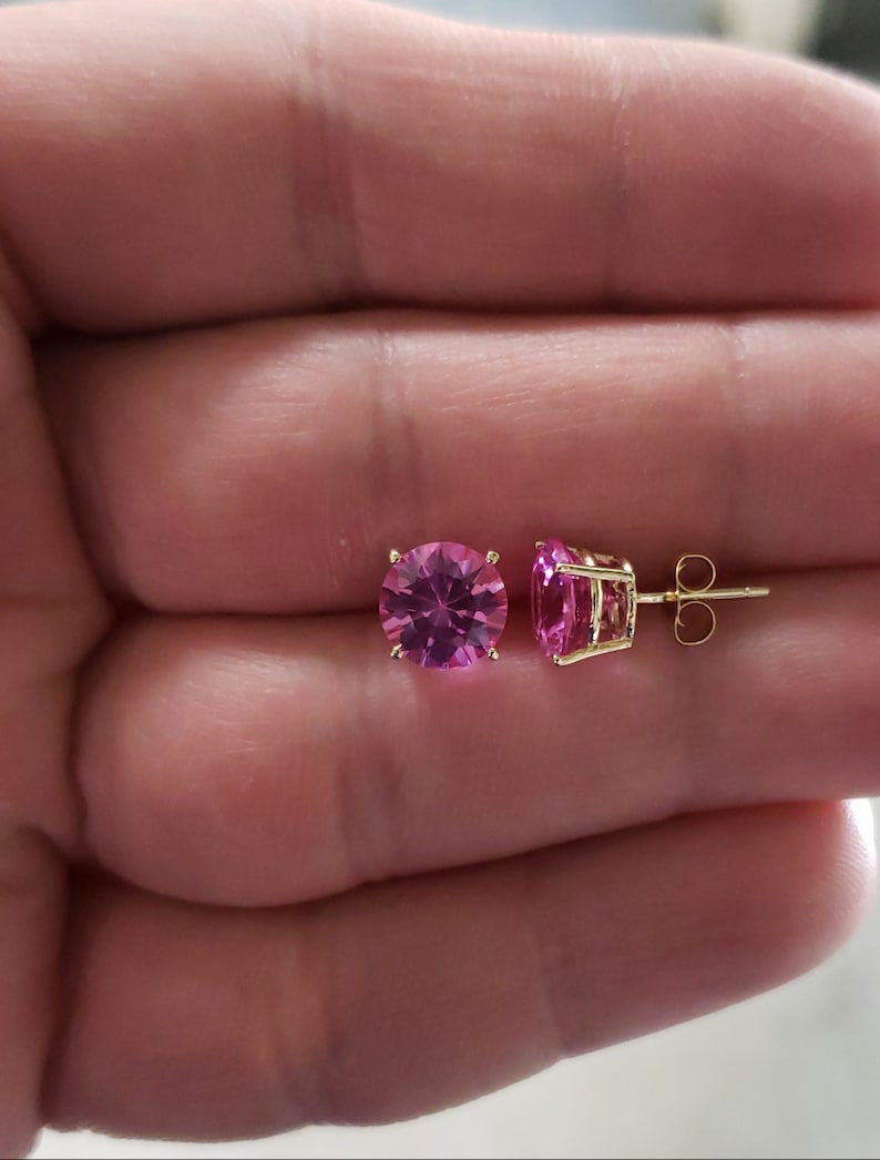 May include: A pair of gold stud earrings with pink round gemstones.