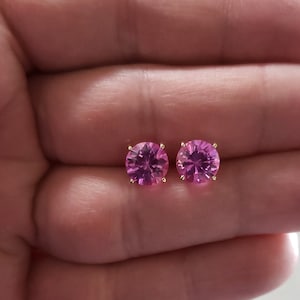 May include: A pair of pink 8mm stud earrings with gold settings. 8mm Size