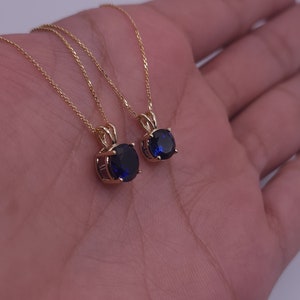 May include: Two gold necklaces with blue oval-shaped gemstones pendants.