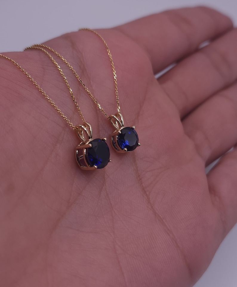 May include: Two gold necklaces with blue oval-shaped gemstones pendants.
