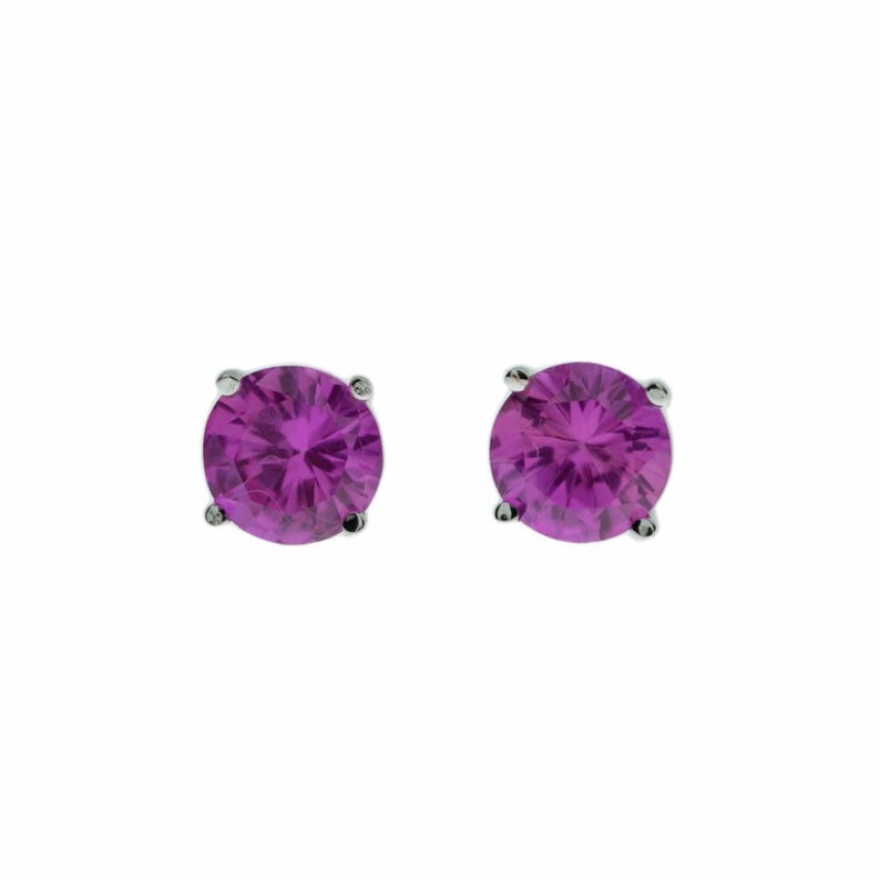 May include: A pair of silver stud earrings with round, purple gemstones.
