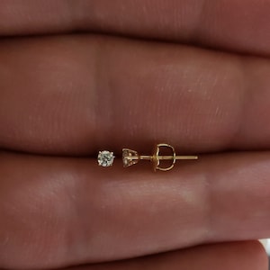 Puede incluir: Un pendiente de oro con un peque&ntilde;o diamante transparente.