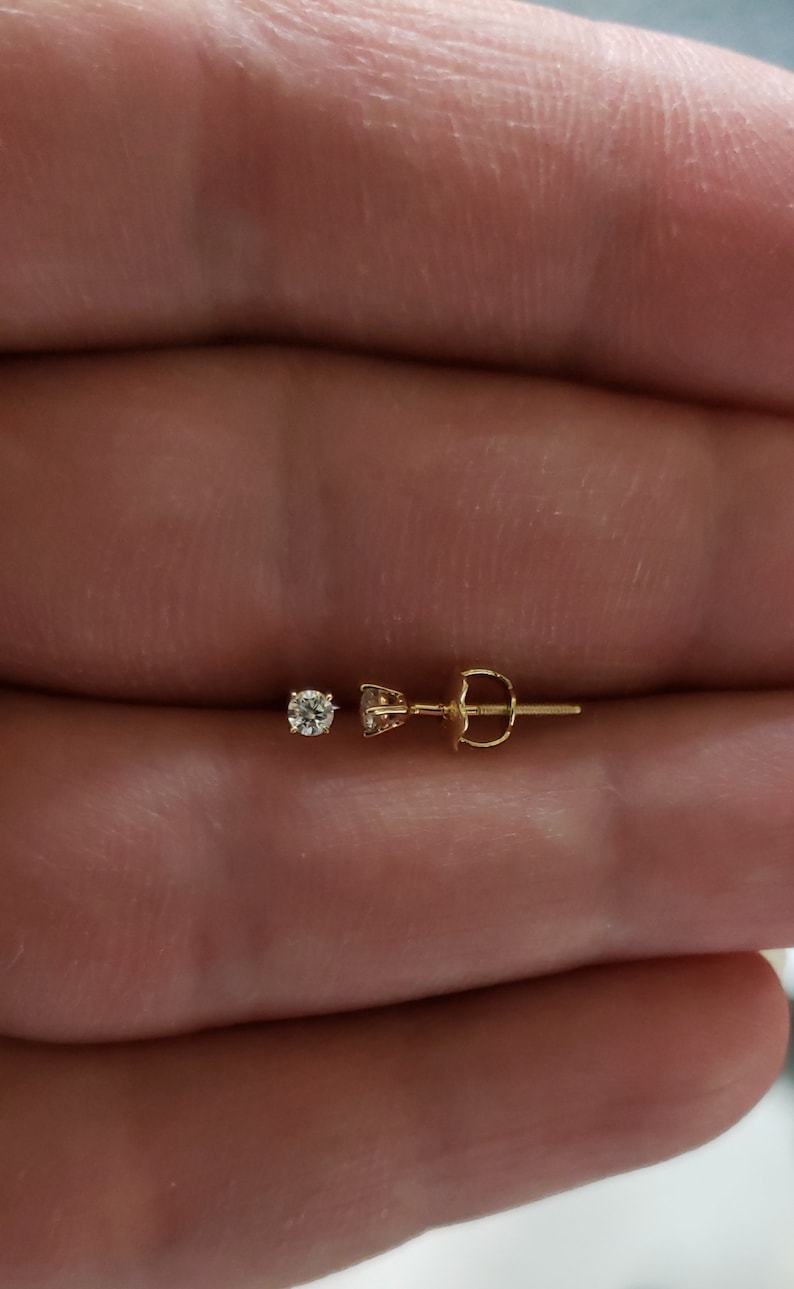 Puede incluir: Un pendiente de oro con un peque&ntilde;o diamante transparente.