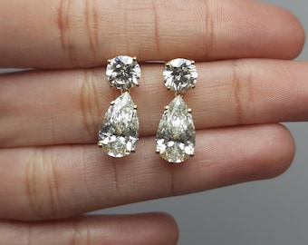 May include: A pair of gold earrings with pear-shaped and round clear cubic zirconia stones.
