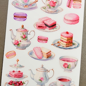 May include: A sticker sheet featuring watercolor illustrations of teacups, teapots, macarons, and cakes. The designs include pink roses and other floral elements. The text "Paperlicious by Su" is visible at the bottom.