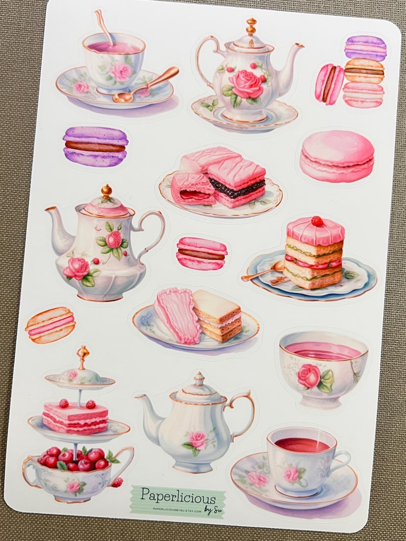 May include: A sticker sheet featuring watercolor illustrations of teacups, teapots, macarons, and cakes. The designs include pink roses and other floral elements. The text "Paperlicious by Su" is visible at the bottom.