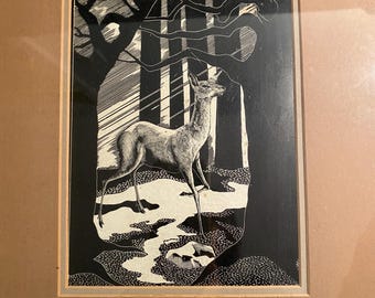 May include: Black and white framed art print of a deer in a forest scene. The artwork features a detailed illustration of a deer standing in a clearing, surrounded by trees. The print is framed in a neutral-toned frame.