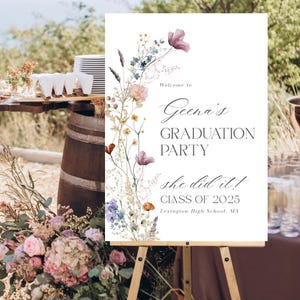 May include: A white sign with a floral border and the text "Welcome to Geena's Graduation Party she did it! Class of 2025 Lexington High School, MA".