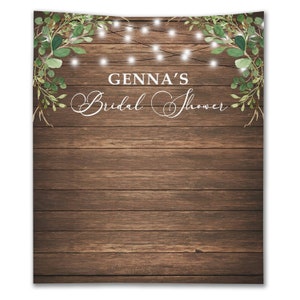 Puede incluir: Fondo de madera r&uacute;stico con una guirnalda de vegetaci&oacute;n y luces de cadena. El texto "GENNA'S Bridal Shower" est&aacute; escrito en letra cursiva blanca.
