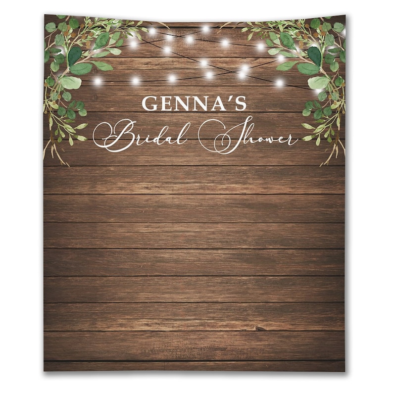 Puede incluir: Fondo de madera r&uacute;stico con una guirnalda de vegetaci&oacute;n y luces de cadena. El texto "GENNA'S Bridal Shower" est&aacute; escrito en letra cursiva blanca.
