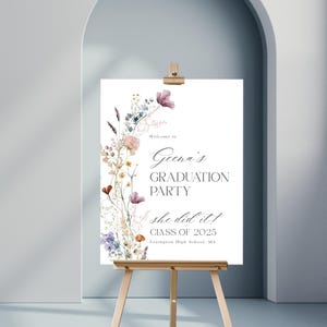 May include: A white sign with a floral border and the text "Welcome to Geena's Graduation Party she did it! Class of 2025 Lexington High School, MA".