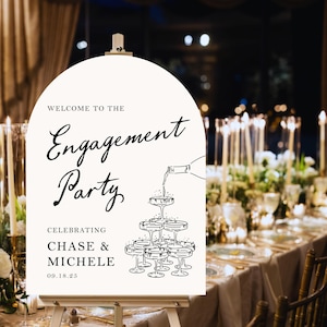 K&ouml;nnte beinhalten: Ein wei&szlig;es Schild mit schwarzem Text und einer Zeichnung von Champagnergl&auml;sern. Der Text lautet "Willkommen zur Verlobungsfeier Zur Feier von Chase & Michele 09.18.25".
