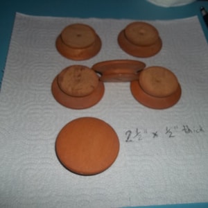 May include: Six round wooden knobs with a diameter of 2 1/2 inches and a thickness of 1/2 inch. The knobs are a light brown color.