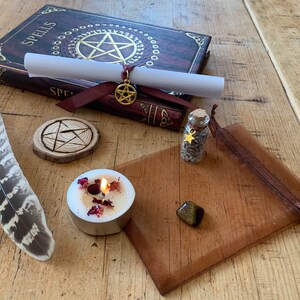 Peut inclure: Un kit de sortil&egrave;ges de sorci&egrave;re avec un livre intitul&eacute; "Spells", un parchemin, un pentagramme en bois, une petite bouteille d'herbes, une bougie, une plume, une pierre &oelig;il de tigre et une pochette brune.