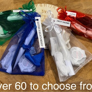 May include: Four small bags made of sheer fabric, each containing a rolled up scroll and a small jar. The bags are tied with ribbons and have labels that say "Love", "Sweet Dreams", "Free Gift", and "Restore a Relationship".