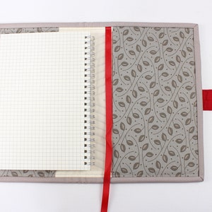 May include: A grey fabric notebook cover with a red ribbon bookmark and a red fabric closure. The cover features a pattern of brown leaves on a light grey background.
