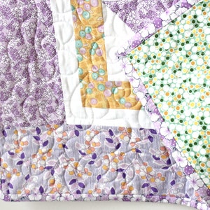 Puede incluir: Una colcha de retazos de color morado, verde y amarillo con un patr&oacute;n floral. La colcha est&aacute; hecha de diferentes telas y tiene un dise&ntilde;o acolchado.