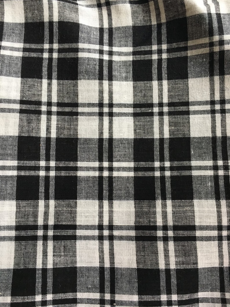 Puede incluir: Primer plano de una tela a cuadros en blanco y negro. El patr&oacute;n presenta una cuadr&iacute;cula de l&iacute;neas que se cruzan, creando un dise&ntilde;o a cuadros. La tela parece estar tejida, con una superficie ligeramente texturizada. La combinaci&oacute;n de colores es cl&aacute;sica: blanco y negro.