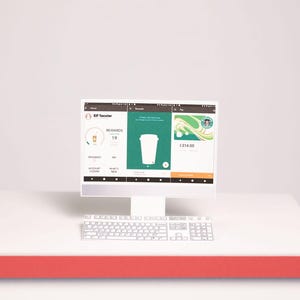 May include: A white computer monitor and keyboard display a mobile application interface with three panels. The screen shows a user profile named Elf Tacolar, a rewards section with a cup icon, and a payment card with a Starbucks logo and 1314.00.