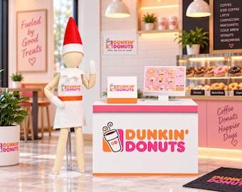 May include: A miniature elf figurine wearing a red hat and white apron stands beside a Dunkin' Donuts counter display. The setup includes a digital menu screen, a branded sign, and a white counter featuring the Dunkin' Donuts logo and coffee cup icon.