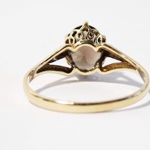 Op de afbeelding: Een gouden ring met een grote ovale edelsteen in een delicate filigraan setting.