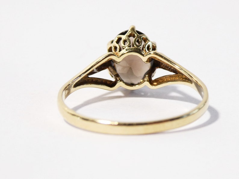 Op de afbeelding: Een gouden ring met een grote ovale edelsteen in een delicate filigraan setting.