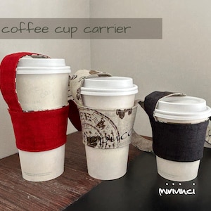 May include: Three fabric coffee cup carriers with handles, each holding a white disposable cup with a lid. The carriers are in solid red, a beige print with coffee-themed text, and solid black. The text "coffee cup carrier" and "mirivinci" appear.