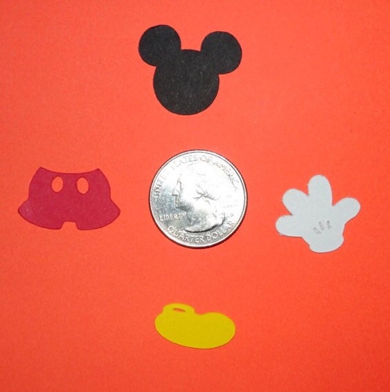 Puede incluir: Cinco recortes de papel con tem&aacute;tica de Mickey Mouse sobre un fondo rojo. Los recortes incluyen la cabeza de Mickey, pantalones cortos, un guante y dos zapatos. Se incluye una moneda de 1 euro para referencia de tama&ntilde;o.