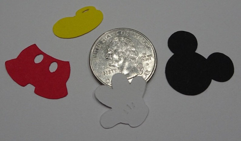 Puede incluir: Cinco recortes de papel de personajes de Mickey Mouse: pantalones rojos, sombrero amarillo, guante blanco y dos orejas negras. Los recortes est&aacute;n dispuestos sobre una superficie blanca junto a una moneda de veinticinco centavos de d&oacute;lar estadounidense para comparar el tama&ntilde;o.