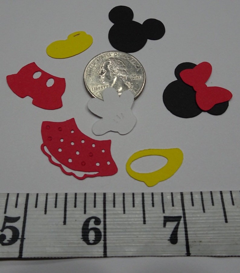Puede incluir: Un conjunto de recortes de papel rojo, amarillo, negro y blanco de los personajes de Mickey Mouse y Minnie Mouse. Los recortes miden aproximadamente 2,5 cm y est&aacute;n dispuestos sobre una superficie blanca junto a una regla.