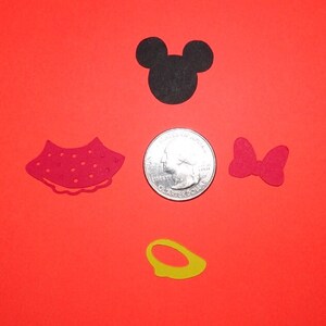 Puede incluir: Un conjunto de cinco recortes de papel con Mickey Mouse y Minnie Mouse. El conjunto incluye una cabeza negra de Mickey Mouse, un vestido rojo de Minnie Mouse, un lazo rojo, un anillo amarillo y una moneda de 20 c&eacute;ntimos de euro para referencia de tama&ntilde;o.