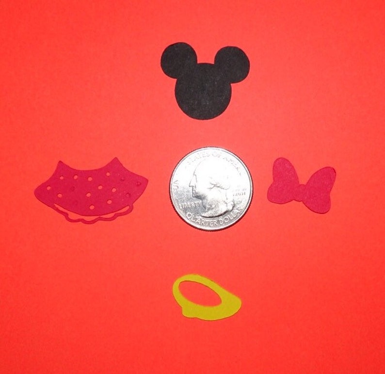 Puede incluir: Un conjunto de cinco recortes de papel con Mickey Mouse y Minnie Mouse. El conjunto incluye una cabeza negra de Mickey Mouse, un vestido rojo de Minnie Mouse, un lazo rojo, un anillo amarillo y una moneda de 20 c&eacute;ntimos de euro para referencia de tama&ntilde;o.