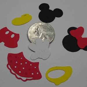 Puede incluir: Un conjunto de recortes de papel rojo, negro, blanco y amarillo con los personajes de Mickey Mouse y Minnie Mouse. Los recortes incluyen la cabeza de Mickey Mouse, sus pantalones cortos y un guante, as&iacute; como la cabeza de Minnie Mouse, su lazo y una falda. Los recortes son aproximadamente del tama&ntilde;o de una moneda de 25 centavos de d&oacute;lar estadounidense.