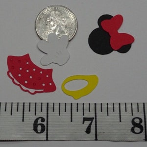 Puede incluir: Un conjunto de seis recortes de papel en varias formas y colores, que incluyen una falda roja con lunares blancos, un guante blanco con lunares negros, un lazo negro y rojo, un anillo amarillo y un c&iacute;rculo negro. Los recortes miden aproximadamente 2,5 cm.