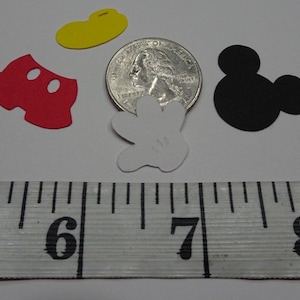 Puede incluir: Un conjunto de cinco recortes de papel con tem&aacute;tica de Mickey Mouse, que incluyen la cabeza de Mickey, pantalones cortos, un guante, un sombrero y una moneda de 25 c&eacute;ntimos para referencia de tama&ntilde;o.